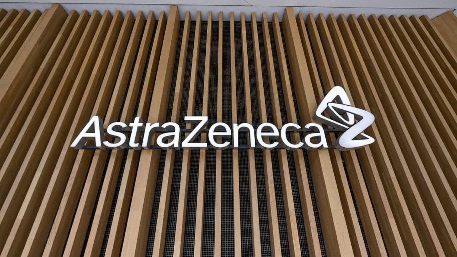 The AstraZeneca name and logo mounted on a slatted timber wall outside a company building. Foto d'archivio.
