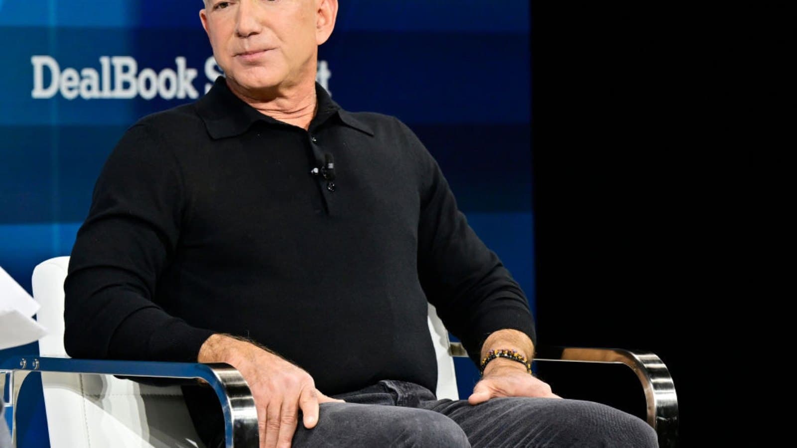 Jeff Bezos seated in a chair on a conference stage in front of a DealBook Summit backdrop. Foto d'archivio.