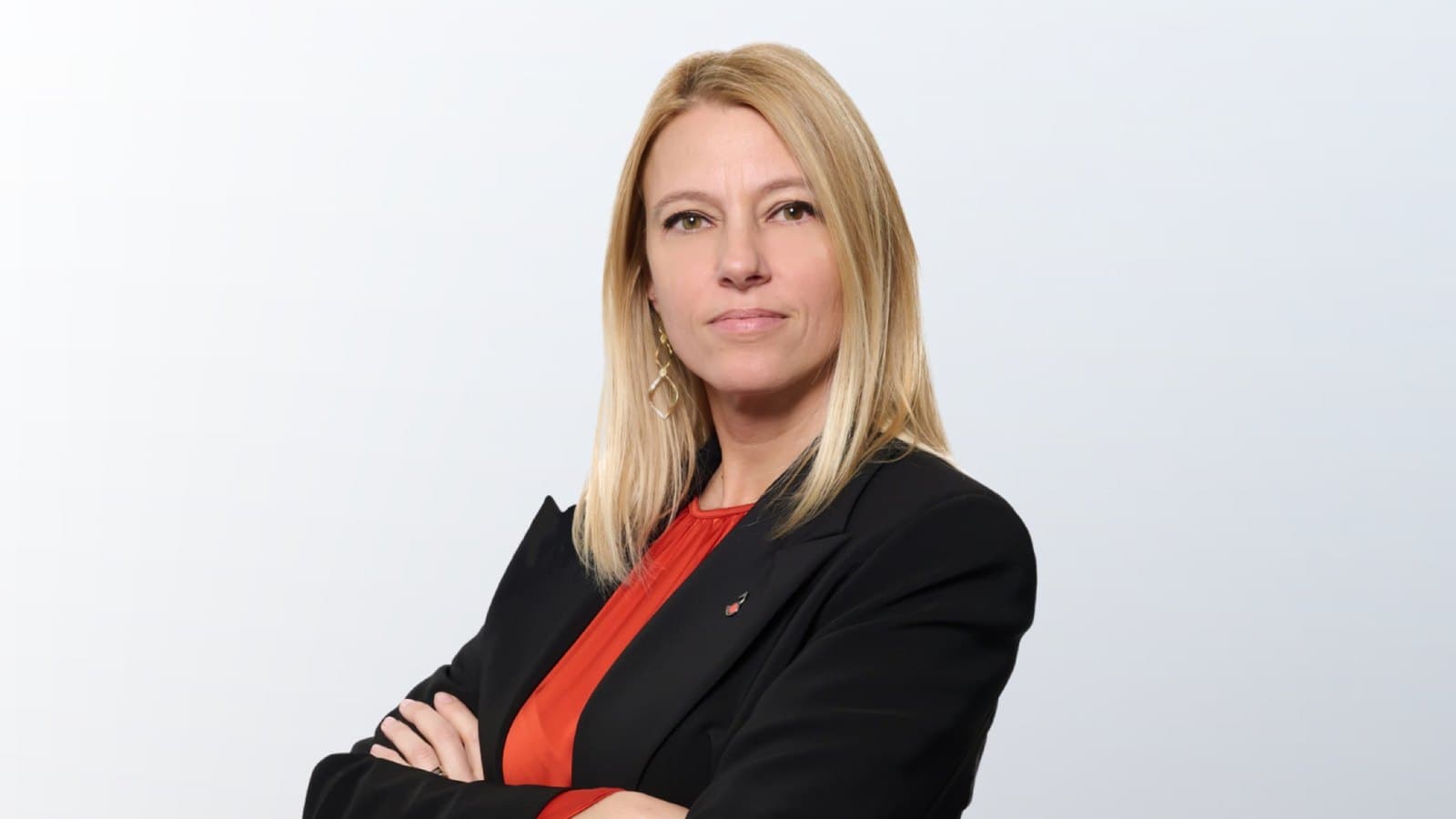 Raffaella Tessari, chief financial officer of Cherry Bank, in a black jacket over a red blouse, arms folded against a pale background.
