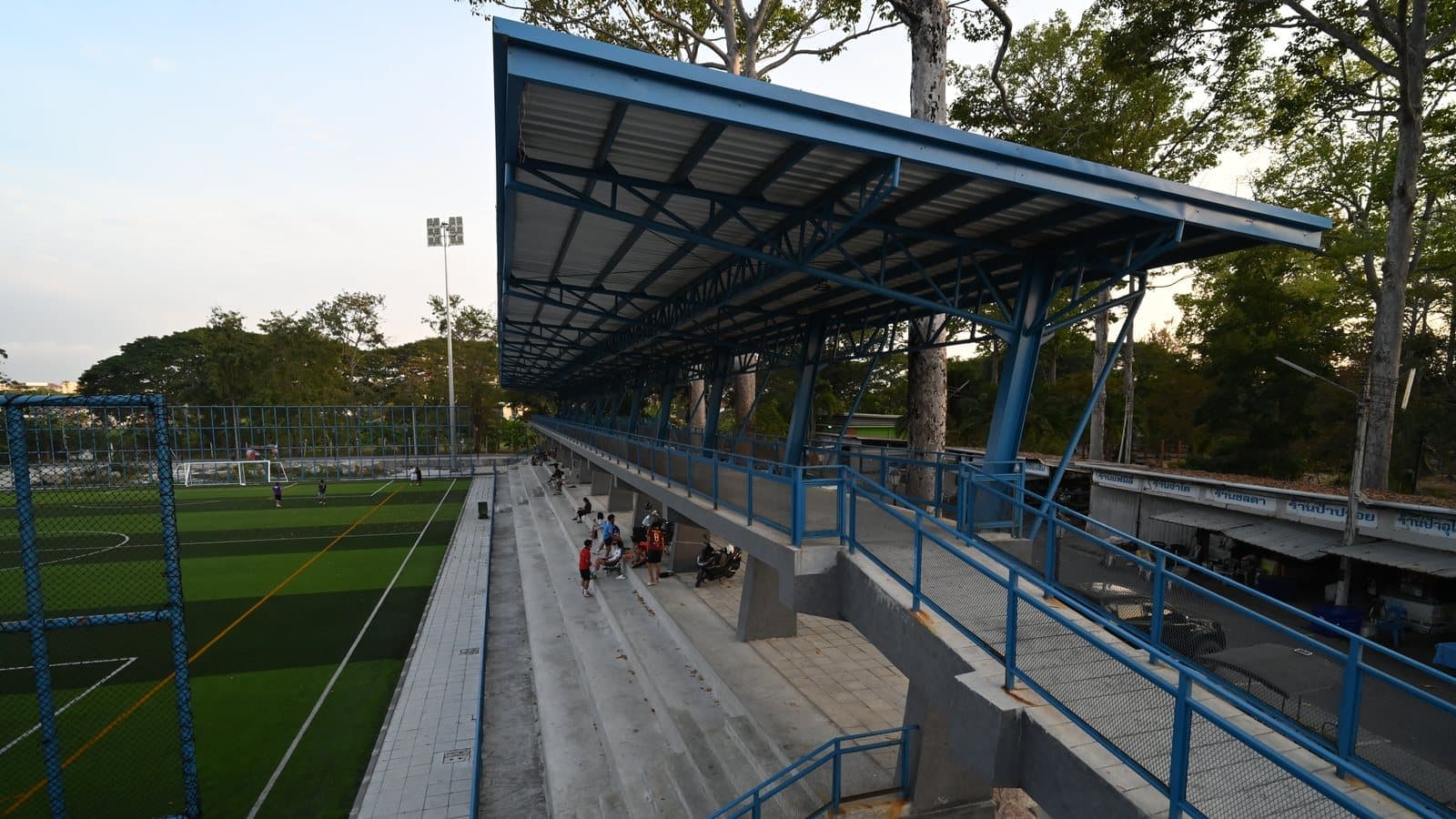 DZ6 2354 Empty bleachers and a covered grandstand overlook a quiet artificial turf sports field at dusk. File photograph. Foto d'archivio.