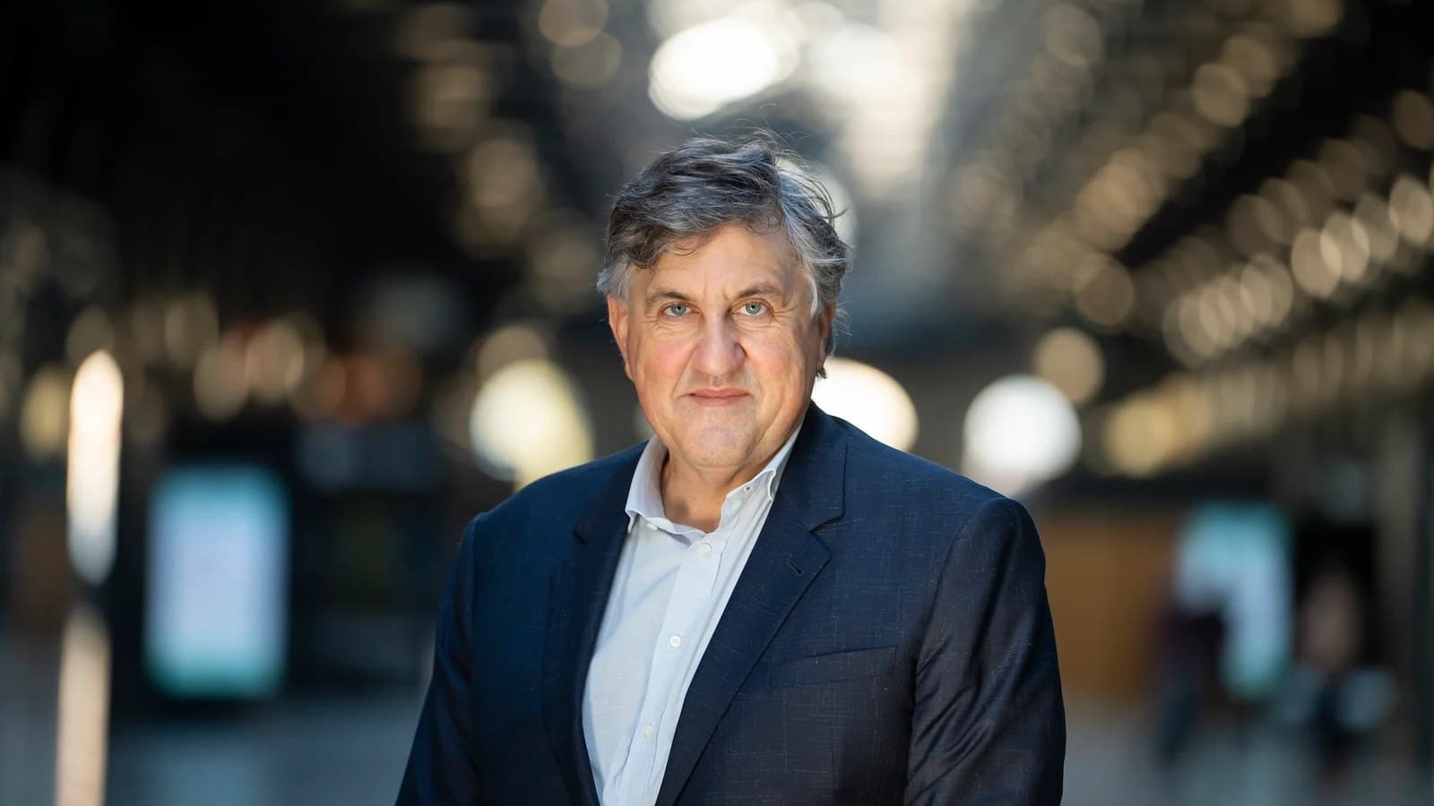 Stefano Buono, founder and chief executive of newcleo, stands in a softly lit atrium in a dark suit.