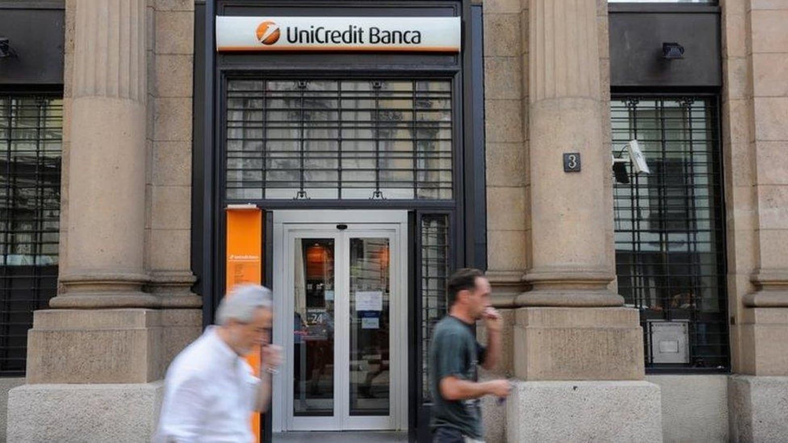 Alcuni pedoni camminano davanti all'ingresso di una filiale di UniCredit Banca in Italia.