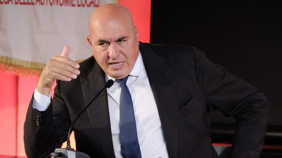 Il ministro della Difesa Guido Crosetto gesticola mentre parla a un podio.
