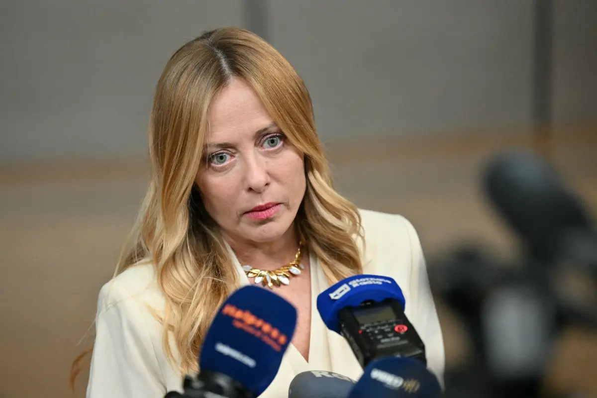 Giorgia Meloni parla ai giornalisti che le avvicinano i microfoni.